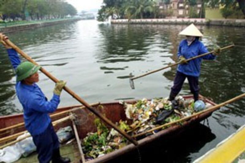 Công nhân vệ sinh hàng ngày phải vớt rác do người dân bỏ xuống hồ ở trung tâm Hà Nội. AFP PHOTO.