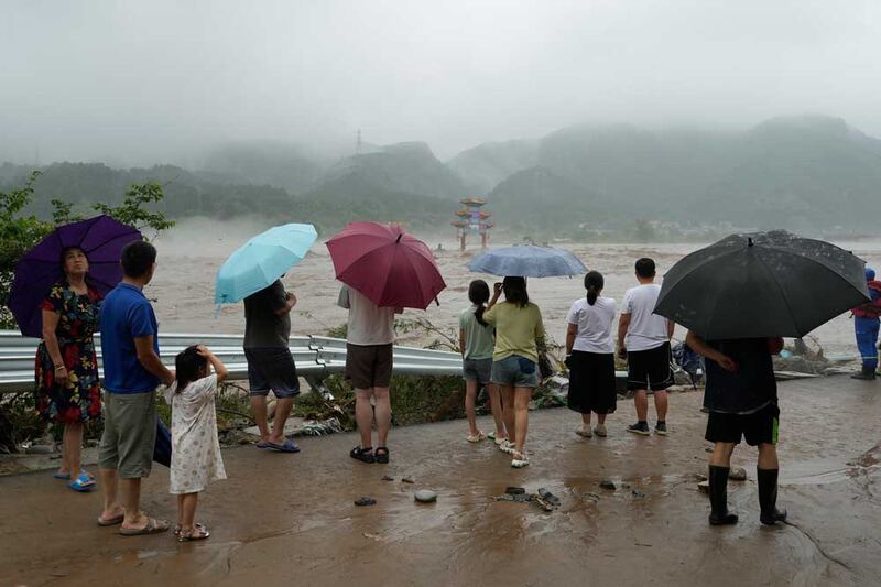 Residents watch floodwaters inundate an area in Miaofengshan on the outskirts of Beijing, Tuesday, Aug. 1, 2023. Credit: Ng Han Guan/AP