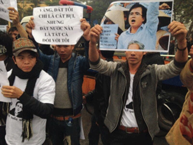 Supporters hold posters with portrait of Le Quoc Quan, Vietnam's leading critic of the Communist regime, outside the court house in Hanoi, Feb.18, 2014.(AFP photo) 