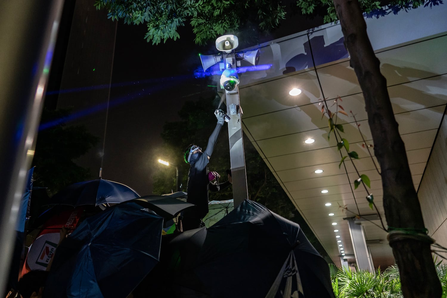 A pro-democracy protester sprays paint over a closed circuit television camera outside the Central Government Complex on September 28, 2019 in Hong Kong.