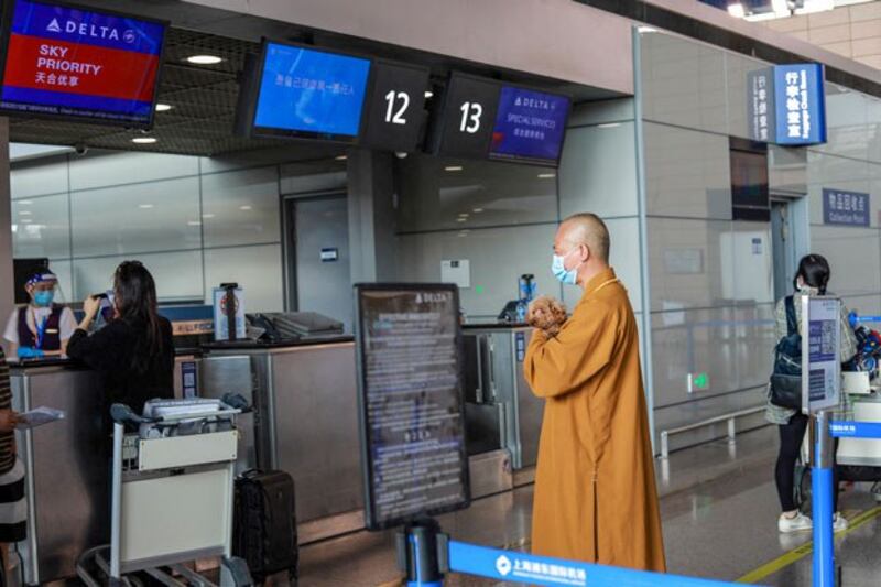 Buddhist monk Zhi Xiang carries a rescued dog before sending him to the United States, at Pudong International Airport in Shanghai, China, May 26, 2021. (Jessica Yang/AFP)