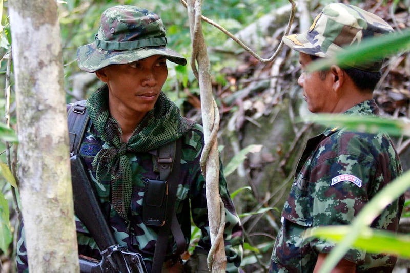 In this April 4, 2009, photo, a Thai soldier, left, looks at a Cambodian solider at the front line of the border where Thai and Cambodian soldiers exchanged rifle and rocket fire near an ancient Hindu temple in Preah Vihear province.