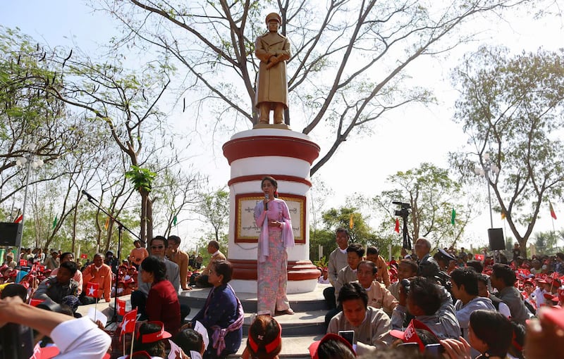 A Feb. 13, 2015, photo shows Aung San Suu Kyi speaking in front of a statue of her father General Aung San to mark his 100th birthday anniversary in his hometown of Natmauk, in Magway district of central Myanmar. This statue was not among those removed.