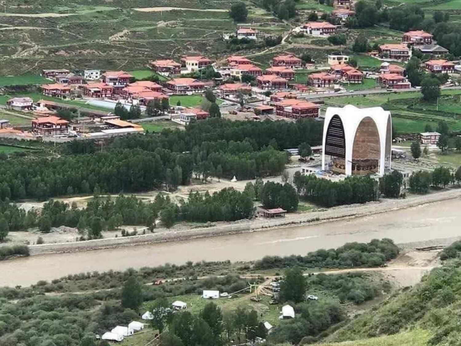 西藏甘孜州炉霍县当局于12月下令拆除当地民众募资建造的一尊高达99英尺的佛像(图中右侧白色建物),遭拆除时被围起来施工。(西藏政策研究中心主任达瓦手仁提供)