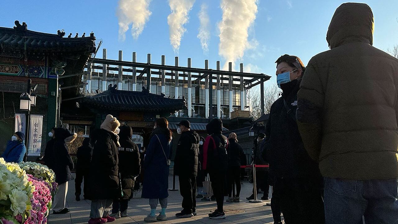 2022年12月31日,北京火葬场的烟囱冒出浓烟,送葬者站在火葬场外。