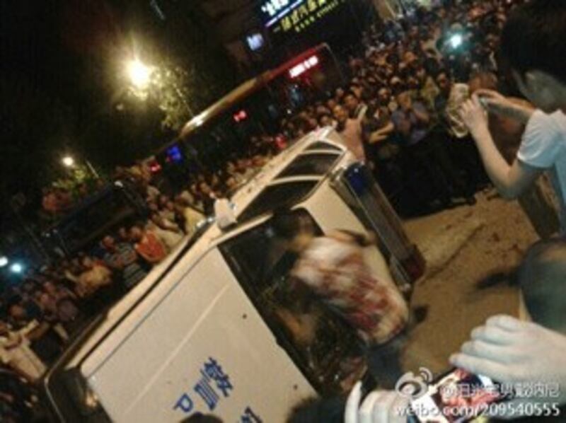 图片: 在现场的一名年轻人用脚踢警车。 (中国茉莉花革命网)