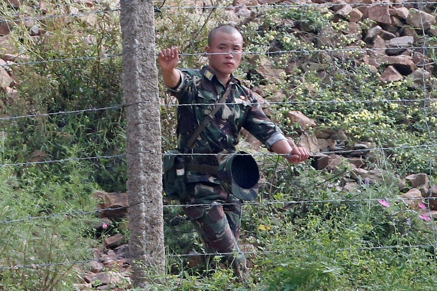 신의주 압록강변에서 한 병사가 철책 너머를 주시하고 있다.