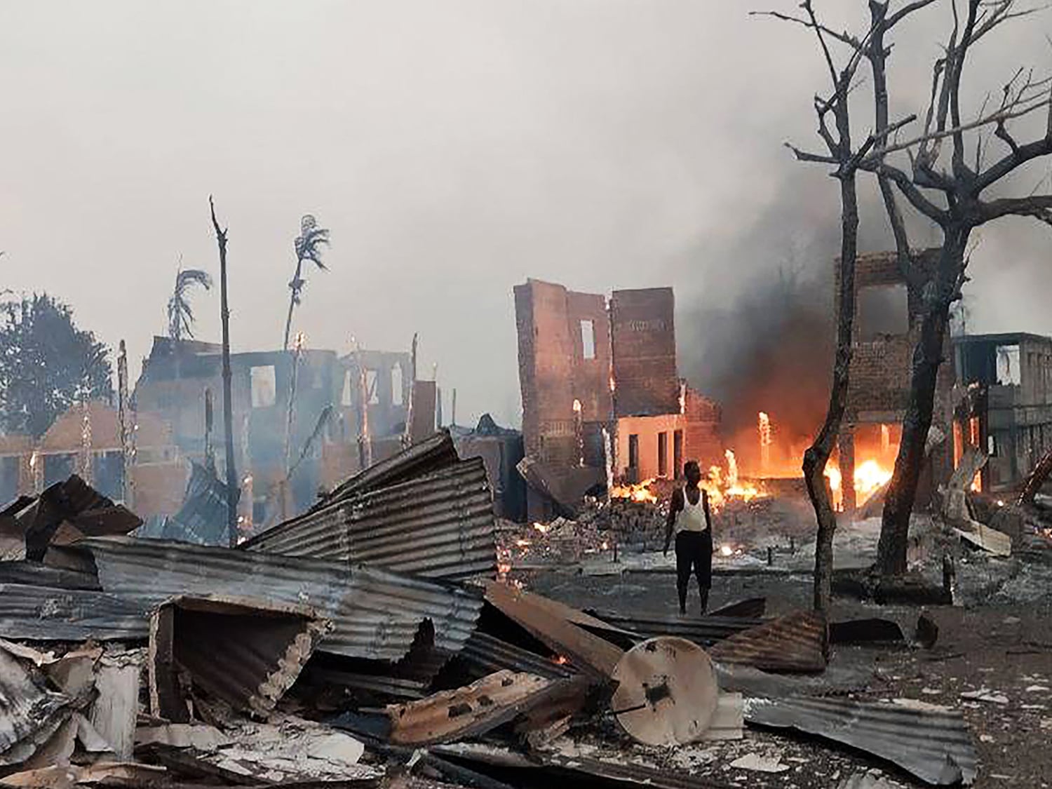 A man stands near a burning house at the site of a suspected airstrike carried out by Myanmar's military on Kyauk Ni Maw village in western Rakhine state, Jan. 9, 2025.