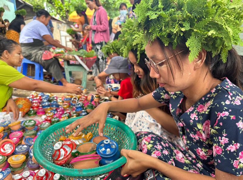 ၂၀၂၃ ခုနှစ် သြဂုတ်လ ၂၄ ရက်နေ့က မန္တလေးတောင်ခြေအနီး အောင်မြေသာစံမြို့နယ် အိုးဘိုရပ်ကွက်မှာ ကျင်းပတဲ့ အိုးပုတ်ပွဲတော်မှာ စျေးဝယ်နေသူတစ်ဦးကို တွေ့ရစဉ်။ (Photo : RFA)
