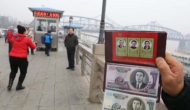 중국 랴오닝성 단둥 압록강대교 인근에서 중국 상인들이 기념품용 북한 모조 지폐를 들어보이고 있다.