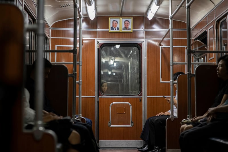 A child looks through a window separating subway train carriages beneath the portraits of late North Korean leaders Kim Il Sung and Kim Jong Il in Pyongyang on June 17, 2019.