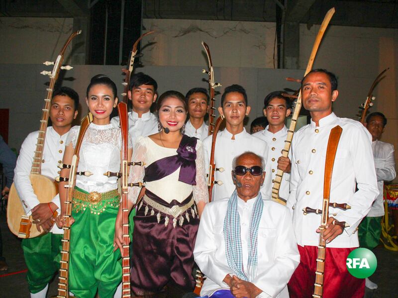 ព្រឹទ្ធាចារ្យផ្នែកចាប៉ីដងវែង លោក គង់ ណៃ (វ៉ែនតាខ្មៅ) ថតរូបអនុស្សាវរីយ៍ក្នុងកម្មវិធីមហោស្រពសិល្បៈ កំណាព្យ និងចម្រៀងខ្មែរជាសកលលើកទី៤ នៅថ្ងៃទី៣ ខែធ្នូ ឆ្នាំ២០១៦។ RFA/Sorn Chanratha