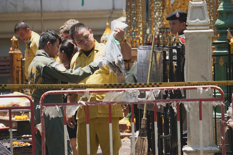 Forensic officials and rescue foundation volunteers clean up the Erawan Shrine in Bangkok, a day after the bomb explosion killed 20 people, Aug. 18, 2015.