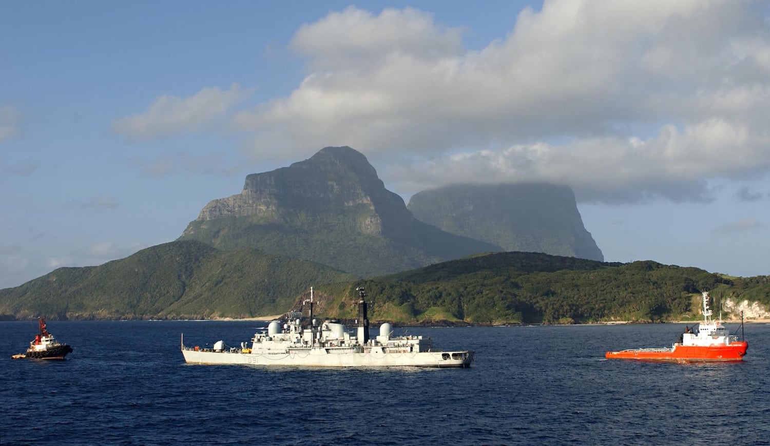 Tugboats assist a damaged British destroyer at Lord Howe Island, Aug. 6, 2002.
