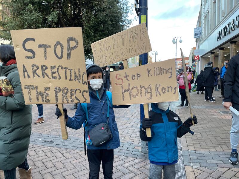 有港人二代手持寫有「停止拘捕記者」(Stop arresting the press)、「爭取自由」(Fight for freedom)、「停止殘殺香港」(Stop killing Hong Kong) 的自製標語參與集會。（呂熙 攝）