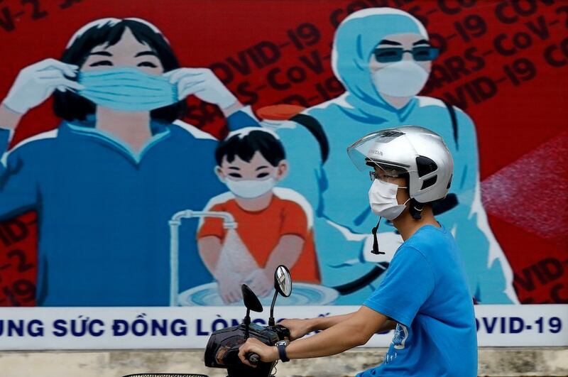 Hình minh hoạ. Người dân đi qua tấm biển kêu gọi phòng chống COVID-19 ở Hà Nội hôm 31/7/2020