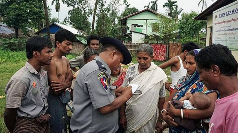 Myanmar Hindus speak to a Myanmar police officer at a makeshift camp after fleeing violence in Maungdaw township, western Myanmar's Rakhine state, Aug. 30, 2017.