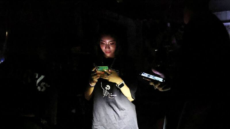 2021年5月13日,台湾台北的一家发电厂停电,一名妇女在停电时使用手机。(路透社)