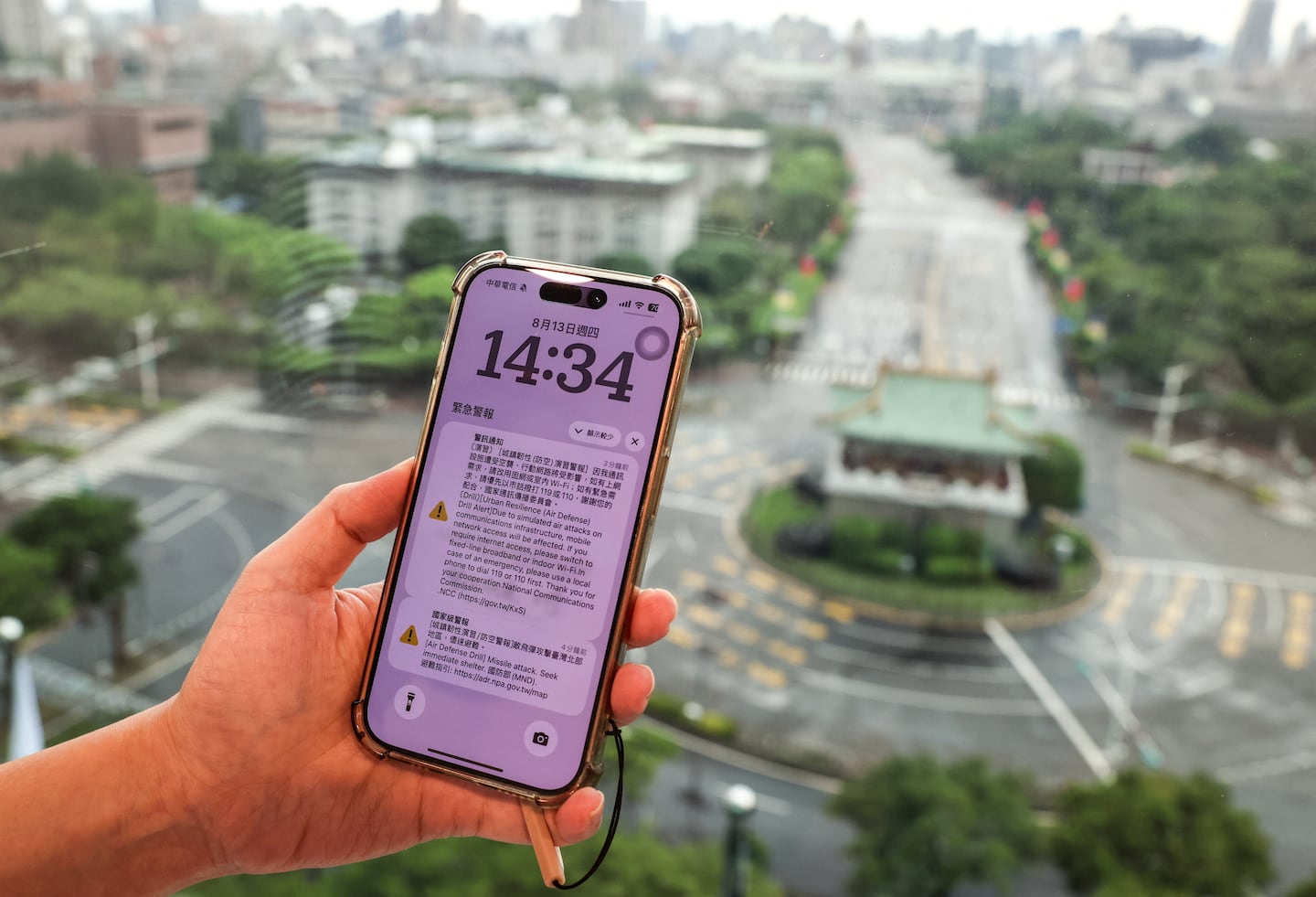 A person holds a mobile phone as streets look empty during an air raid drill in Taipei on Aug. 13, 2026. Millions of people in Taiwan were forced indoors and mobile internet speeds slowed for 30 minutes on August 13, during a simulation of a Chinese attack on the island democracy. The drill was part