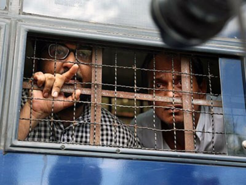 Myanmar interpreter Aung Naing Soe (L) and driver Hla Tin (R) look out from a prison transport vehicle after they are sentenced to two months in prison for illegally flying a drone, in a court in Naypyidaw, Nov. 10, 2017.