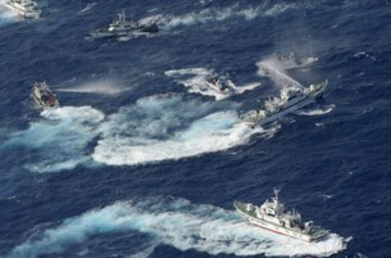 图片：台湾保钓船队周二到达钓鱼岛周边海域。日本海上保安厅的舰艇以水柱喷射保钓船，护航的台湾海巡署舰艇也以水柱回击。（法新社）