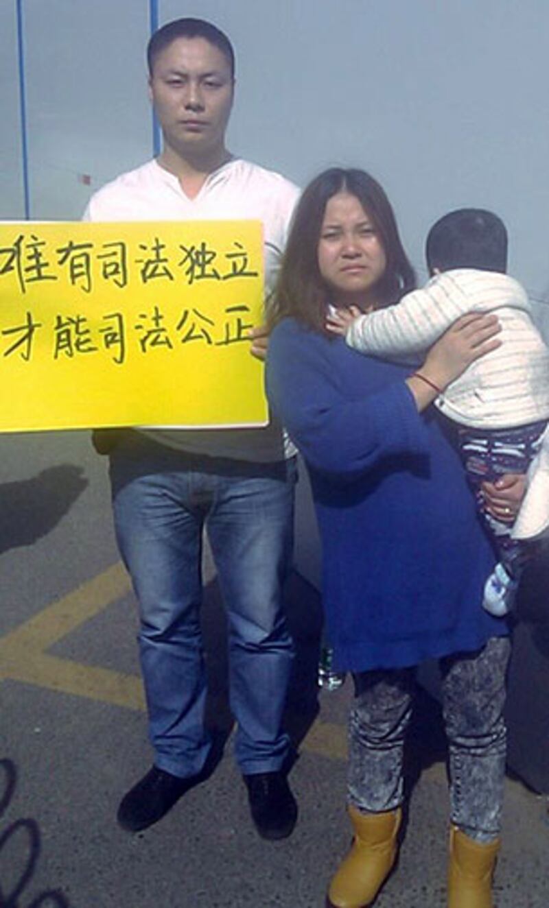 王登朝妻子帶同七個月大的兒子到法院旁聽。一名聲援者（左）因舉起標語被拘留。（賴先生提供）