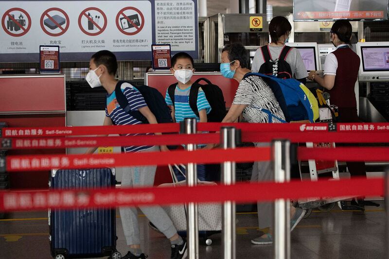 2020年6月17日,戴着口罩的乘客在北京首都机场3号航站楼办理登机手续。(美联社)