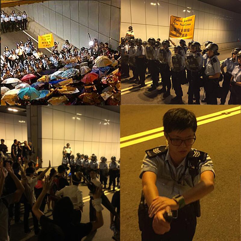 金鐘佔中集會區示威者，週二(14日)晚上，與大批帶頭盔及持盾牌的警員發生衝突，警方舉起警告牌，並一度使用胡椒噴霧驅散示威者。 (圖片來自學民思潮臉書﹐2014年10月14日)