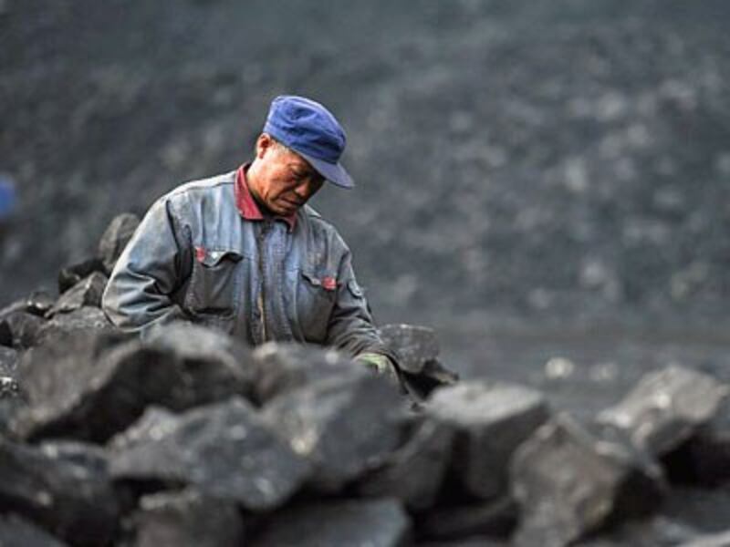 A Chinese worker sorts coal on a conveyor belt near a coal mine in Datong, northern China's Shanxi province, Nov. 20, 2015.