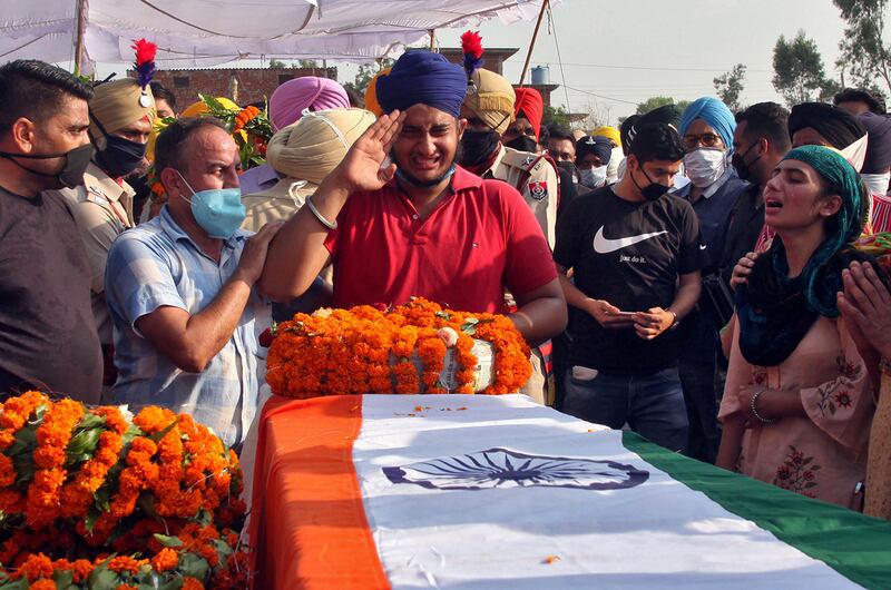 Prabhjot Singh, son of Satnam Singh, an Indian soldier who was killed in a border clash with Chinese troops in the Ladakh region, reacts next to the coffin of his father during his funeral ceremony in Bhojraj village in Gurdaspur, Punjab, June 18, 2020.