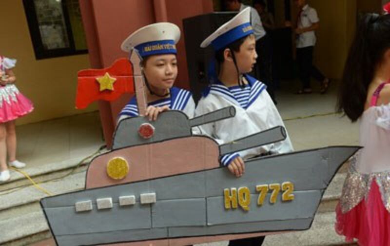 Hai học sinh trong đồng phục một trường học ở Hà Nội với mô hình giấy tàu hải quân Việt Nam trong một tiết mục văn nghệ nhân ngày khai giảng năm học mới hôm 5/9/2016. AFP photo