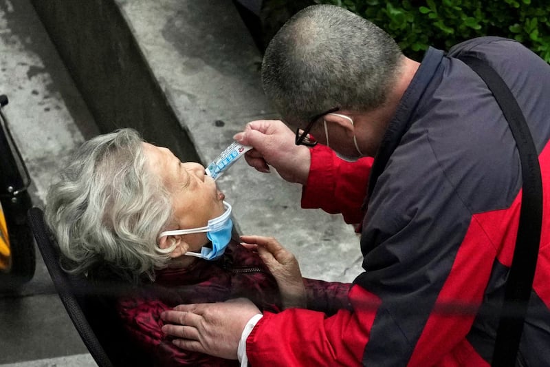 2022年4月5日,上海封城期间,路边一位老人在帮助下服用中成药连花清瘟颗粒。 (路透社图片)