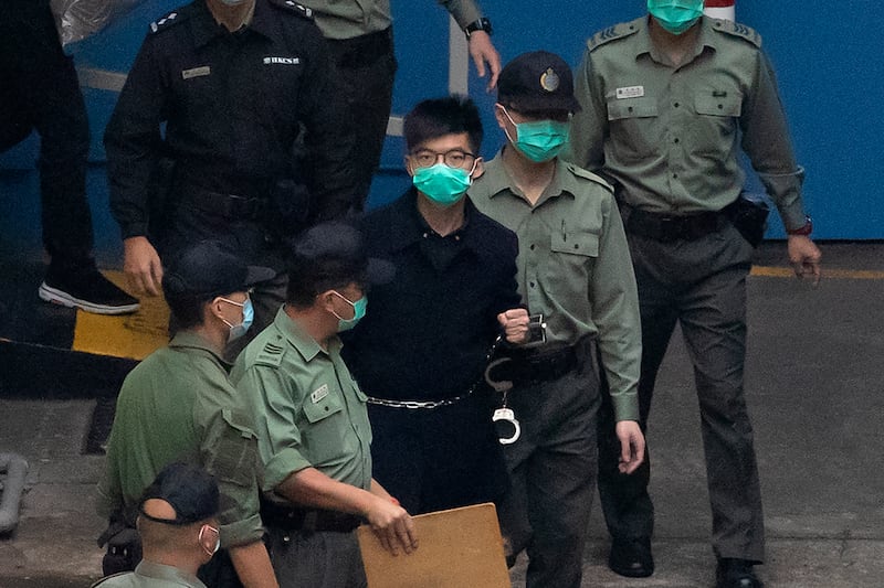 In this March 4, 2021, photo, Hong Kong activist Joshua Wong, is escorted by Correctional Services officers to a prison van in Hong Kong.
