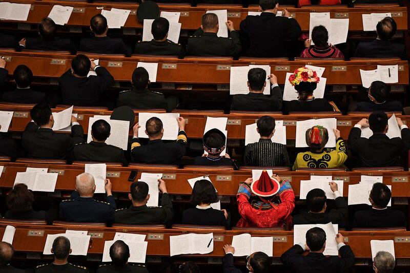 图为,2021年3月4日,在北京人民大会堂举行的中国人民政治协商会议(CPPCC)开幕式上代表们宣读报告。(法新社图)