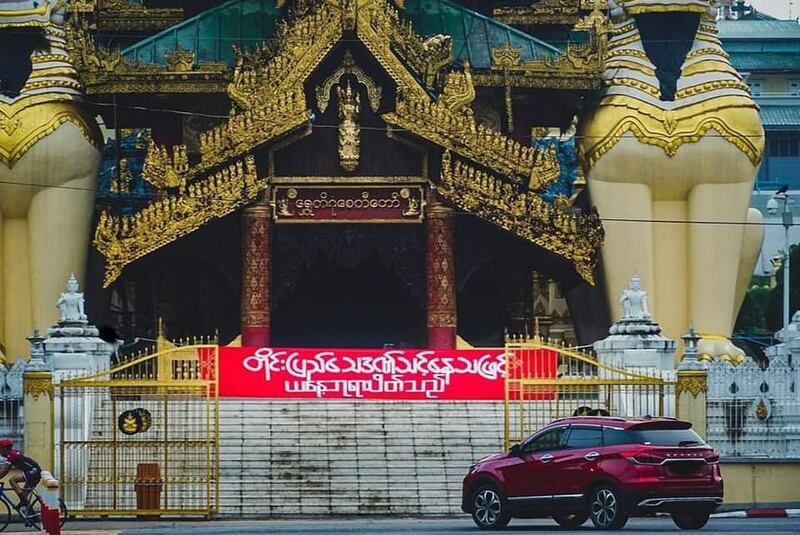 ရန်ကုန်မြို့ ရွှေတိဂုံစေတီတော် တောင်ဘက်မုခ်ဦးဝမှာ "တိုင်းပြည် သေဒဏ်သင့်နေသဖြင့် ယနေ့ ဘုရားပိတ်သည်" ဆိုသည့် စာတန်းချိတ်ဆွဲထားတာကို ၂၀၂၂ ခုနှစ် ဇွန်လ ၁၃ ရက်နေ့မှာ တွေ့ရစဥ် (Photo: Yangon People's Strike)