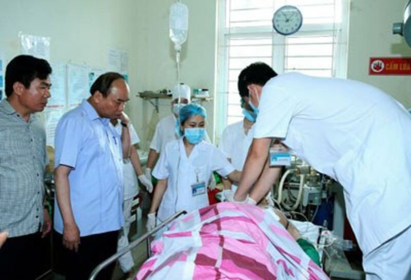 Thủ tướng Việt Nam Nguyễn Xuân Phúc (thứ hai từ trái) bên nạn nhân Phạm Duy Cường tại bệnh viện Yên Bái sáng 18/8/2016. AFP