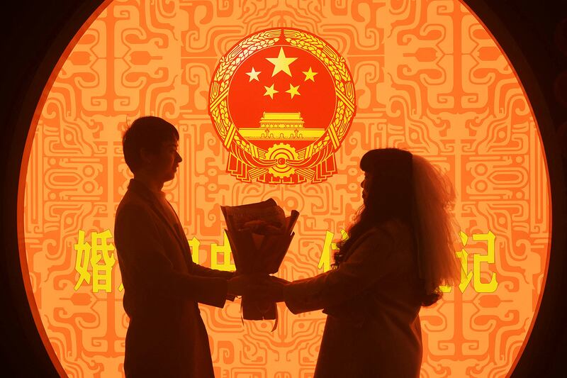 A newlywed couple pose for pictures on Valentine's Day at a marriage registration office in Hangzhou, Zhejiang province, China, Feb. 14, 2023.