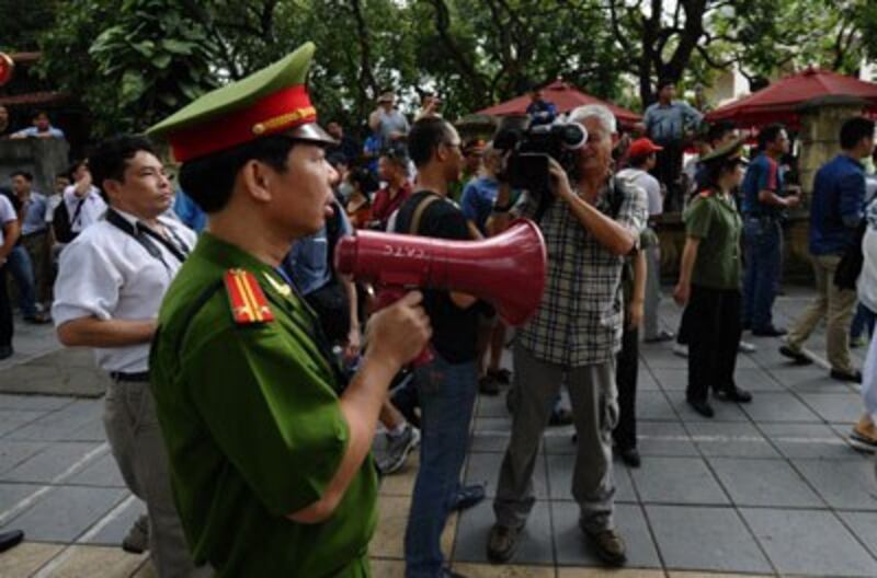 Công an dùng loa yêu cầu mọi người không tụ tập trên một đường phố gần đại sứ quán Trung Quốc tại Hà Nội ngày 18 tháng 5 năm 2014. AFP photo 