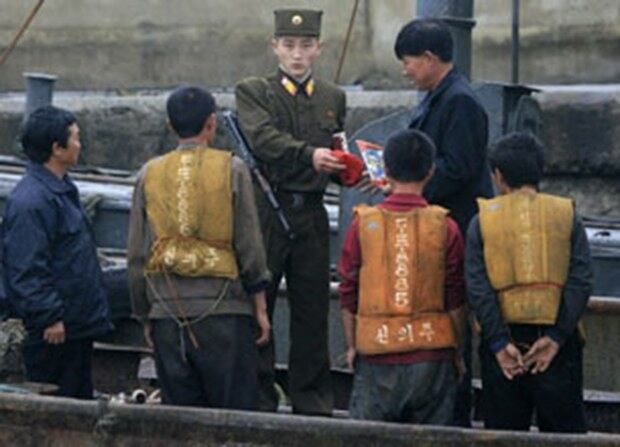 사진은 북한 국경경비병이 중국에서 배를 타고 압록강을 건너온 사람들의 서류를 조사하고 있는 모습.