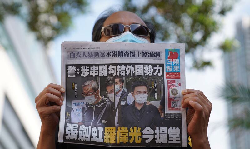 2021 年 6 月 19 日,《苹果日报》总编罗伟光、壹传媒行政总裁张剑虹遭正式起诉后,一名支持者在西治安法院外持有一份苹果日报的副本。(路透社)