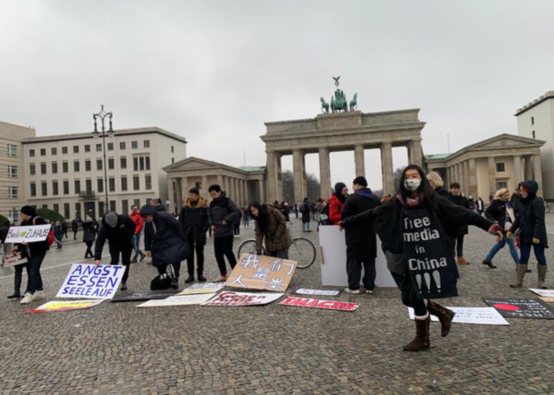 2020年2月14日，藝術家丹暘在柏林勃蘭登堡門前身披要求中國「媒體自由」的條幅。當時一群在德華人藝術家發起反德國歧視行為藝術，疑為中國當局模糊武漢疫情焦點。丹暘認為真正歧視和漠視公眾權利的是中共當局，她要求當局公示疫情資訊，開放媒體自由。（吳亦桐 攝）