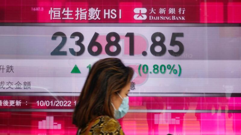 一名女子走过香港的股票电子显示牌。(美联社)