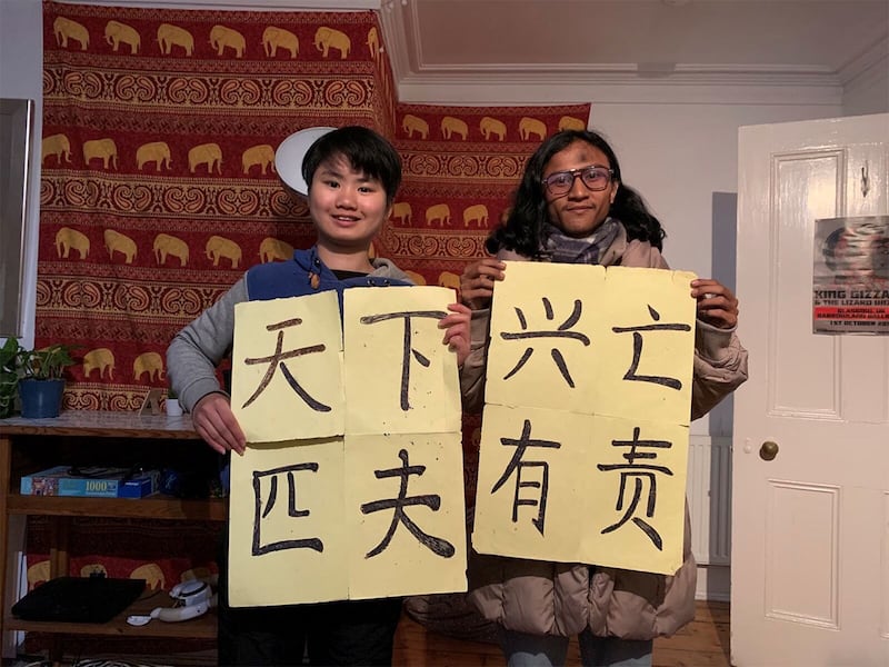 欧泓奕（左）拿出游行时的中文标语，与印度尼西亚气候活动家交流彼此的气候行动。（欧泓奕提供）