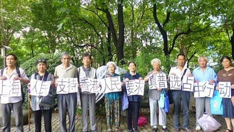2014年9月24日，十多名上海訪民，包括胡伯森、談蘭英、劉淑珍、陳建芳等，在上海人民公園，舉起寫有支持香港真普選及佔中的紙張，呼籲大陸民眾支持港人。(現場人士攝)