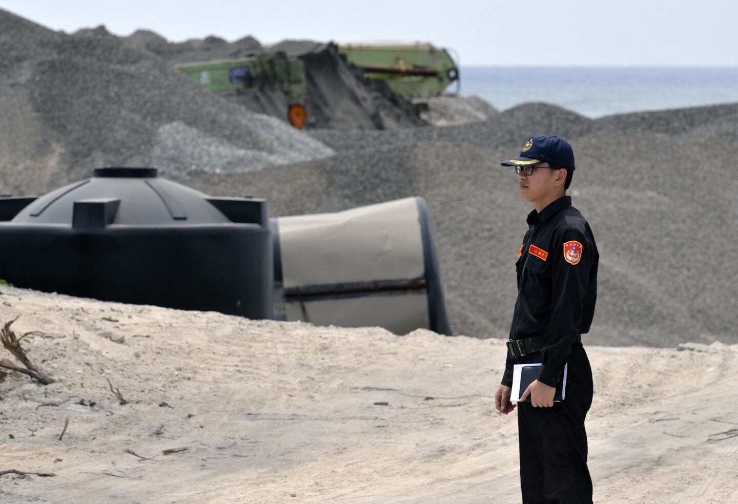 A member of Taiwan's coast guard stands at the entrance of a construction site as he guides visiting journalists on Taiping island in the Spratlys chain in the South China Sea on March 23, 2016.