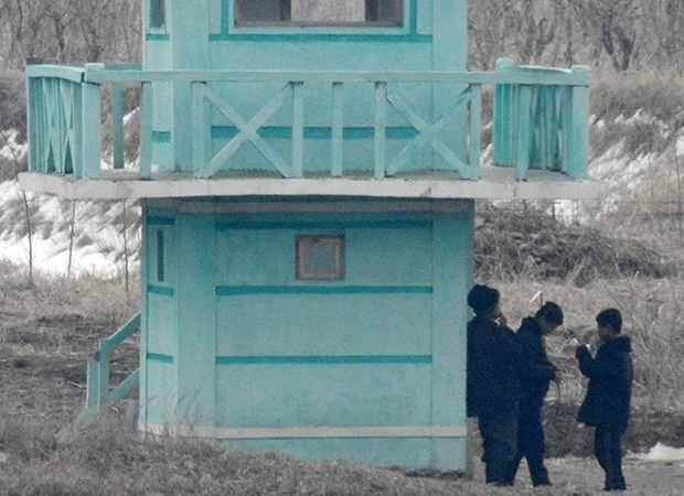 중국 랴오닝성 단둥 외곽에서 바라본 북한지역에서 북한 주민들이 담배를 피고 있다.