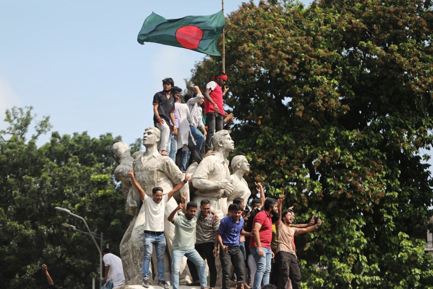 Protesters raise the Bangladesh flag after Prime Minister Sheikh Hasina resigned, amid student-led protests that turned deadly after security forces and supporters of her Awami League party clashed with demonstrators, in Dhaka, Aug. 5, 2024.