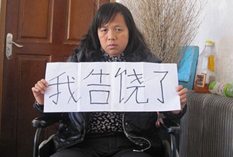 黑龍江訪民陳慶霞被拘禁在伊春巿帶岭區醫院太平間近三年，她舉牌投降。（照片來自維權人士，2012年11月拍攝）