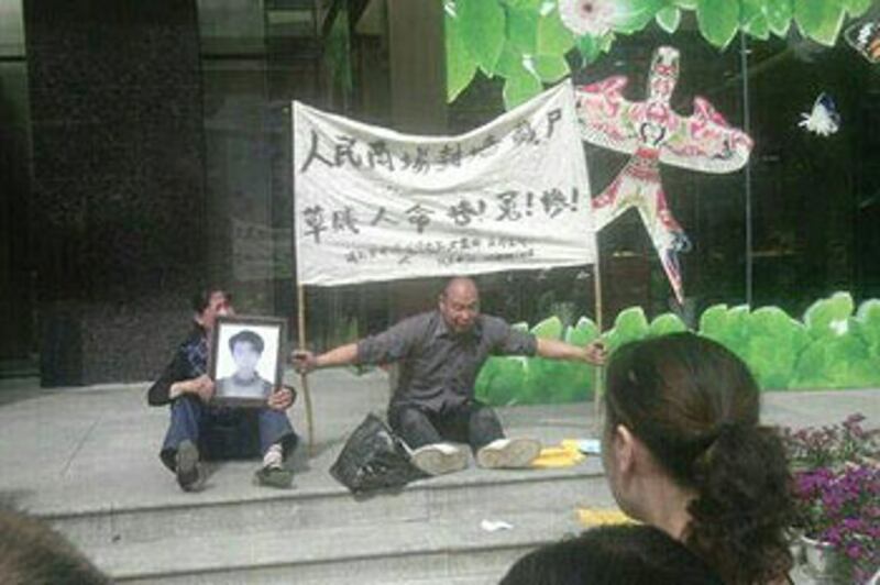 2012年5月15日,湖北十堰市,死者段天勇的雙親手持遺像和橫額,要求政府交代兒子屍首藏於商場夾縫真相。(死者段天勇家人提供)