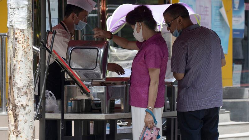 中国经济复苏后又面临困难。图为2020年6月30日北京居民在路边购买食物。（美联社）